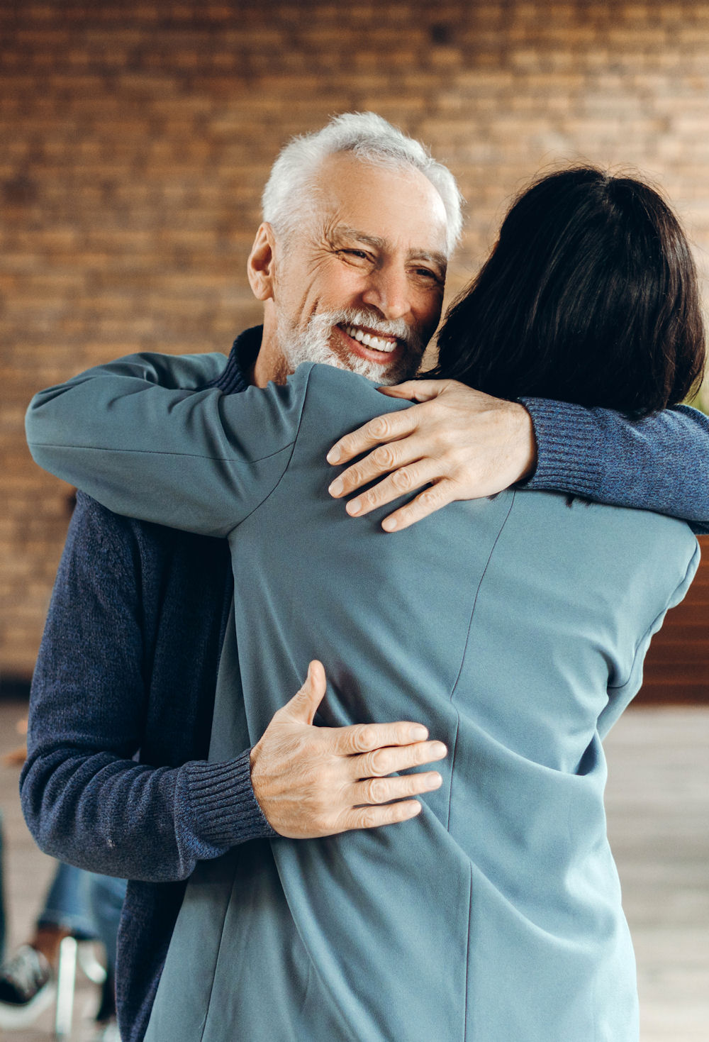 Senior man and businesswoman hugging during group therapy session