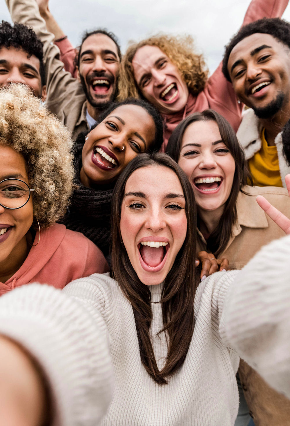 Multiracial friends taking big group selfie shot smiling at came